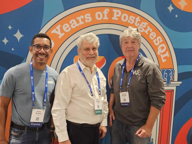Euler Taveira, Bruce Momjian, and Tom Kincaid pose for a group picture in front of a banner that reads 30 Years of PostgreSQL